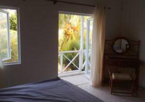 ein Schlafzimmer mit einem Bett und einem großen Fenster in der Unterkunft appartement lagon blue in Mahébourg