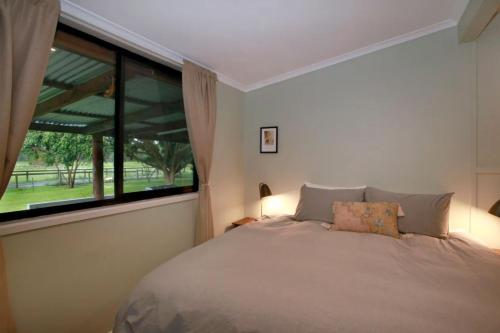 a bedroom with a bed and a large window at Sahara Trails House WiFi Air Conditioning Horse Riding and much more in Anna Bay