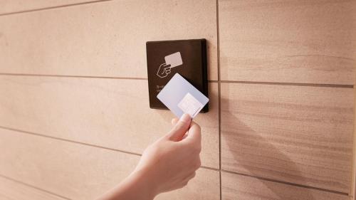 a person holding a credit card in front of a wall at JR-East Hotel Mets Musashisakaii in Musashino