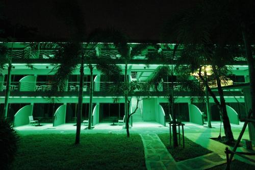a lit up building with palm trees in front of it at Momento Resort in Pattaya South