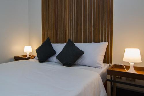 a bedroom with a white bed with two lamps at Z Hostel in Manila