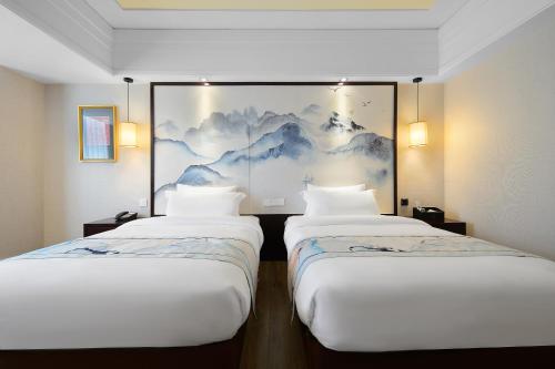 two beds in a room with a painting on the wall at Foshan Rezen Select Pasonda Hotel in Foshan