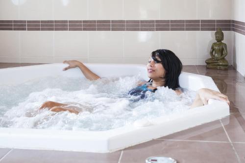 Eine Frau sitzt in einer Badewanne in der Unterkunft Vacancéole - Le Domaine des Grands Lacs in Parentis-en-Born