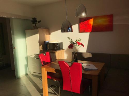 a dining room with a table and red chairs at Appartement Schusternagele in Amlach