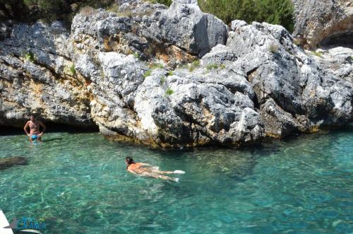 two people swimming in the water near some rocks at Hotel Calanca in Marina di Camerota