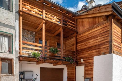 a wooden building with potted plants on a balcony at Appartamento Tobià in Pozza di Fassa