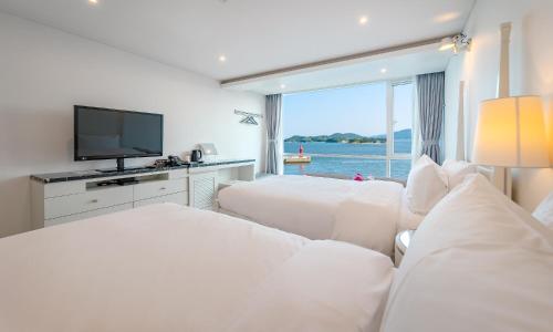 pokój hotelowy z 2 łóżkami i telewizorem z płaskim ekranem w obiekcie Owl Hotel w Sacheon