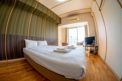 1 dormitorio con 1 cama grande y TV en S-Presso Namba Parks Street, en Osaka