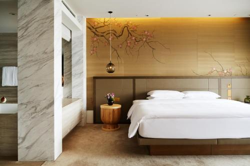 a bedroom with a large bed and a bathroom at Grand Hyatt Hong Kong in Hong Kong