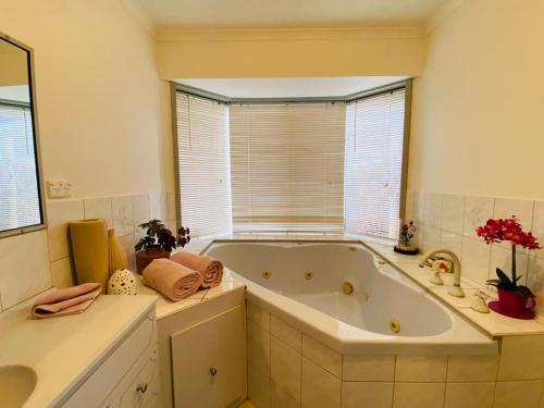 a large bath tub in a bathroom with a window at ENTIRE HOME IN WERRIBEE,BEST POSSIBLE LOCATION YOU CAN FIND in Werribee