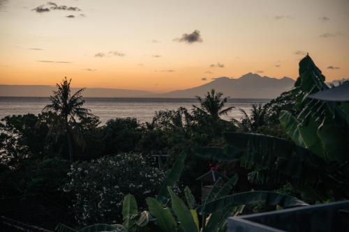 a sunset over the ocean with mountains in the background at Bukit Indah Homestay in Amed