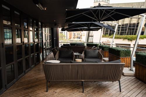 a patio with chairs and an umbrella on a building at The Capital Trilogy Menlyn Maine in Pretoria