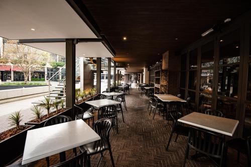 a restaurant with tables and chairs in a room at The Capital Trilogy Menlyn Maine in Pretoria