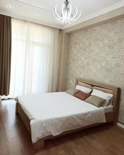 a bedroom with a large white bed with a chandelier at Престижная квартира Кара Караева in Baku