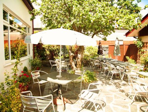 a patio with tables and chairs and an umbrella at Royal Sportsman Hotel in Porthmadog