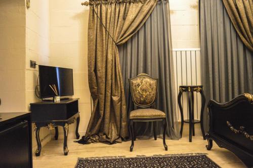una silla en una habitación con cortinas y TV en Aslanbey Konağı Butik Otel, en Acırlı