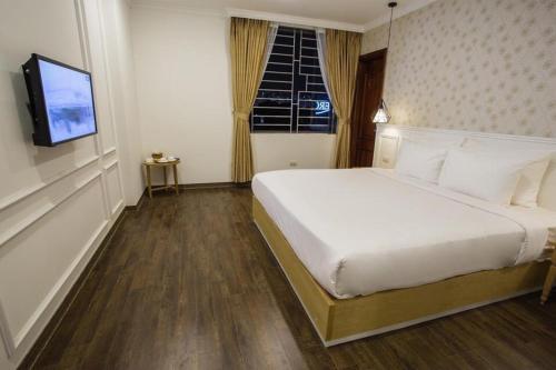 um quarto com uma cama branca e uma televisão em Khách Sạn A83Hotel em Hanói