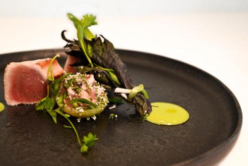 a black plate with a piece of food on it at Hôtel Restaurant Gastronomique La Huchette in Mâcon