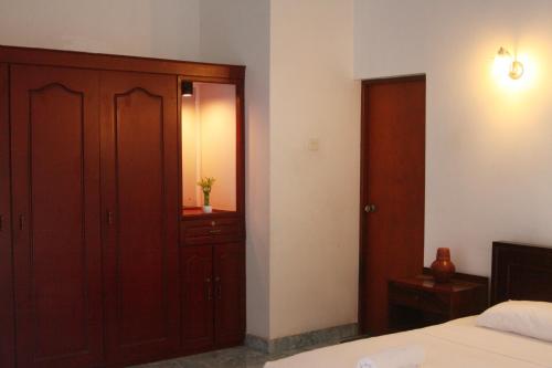 a bedroom with a bed and a wooden cabinet at Natures Bliss Holidays in Ja-Ela