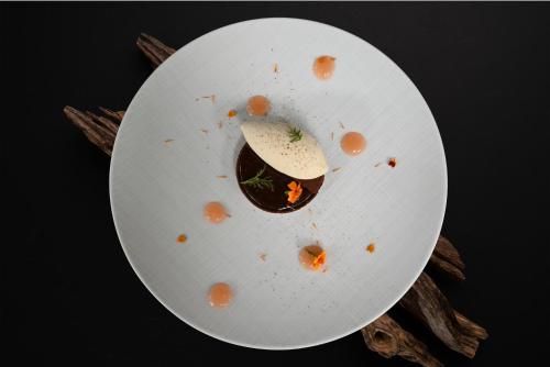 a white plate with a piece of food on it at Hôtel Restaurant Gastronomique La Huchette in Mâcon