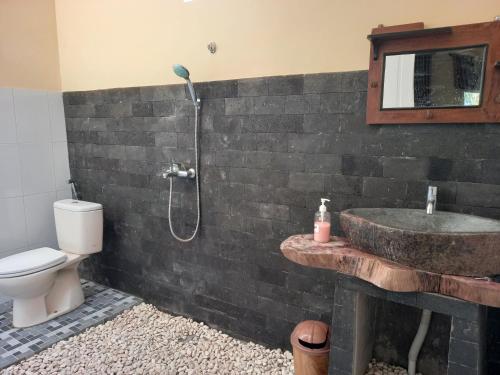 y baño con lavabo, aseo y ducha. en TelukBiru Homestay en Banyuwangi