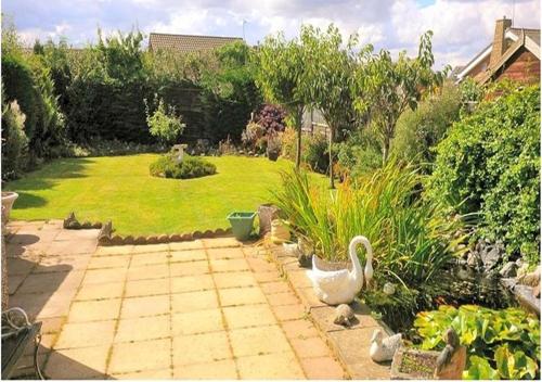 a garden with a patio with a swan in the middle at Coconut Cottage - A Romantic Cosy Cottage by the Sea! - You'll love this adorable Seaside Gem Just a few steps from the Beach! Perfect for Couples & Family's in Sutton on Sea