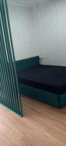 uma cama verde num quarto com piso em madeira em NEW STAIL em Bălţi