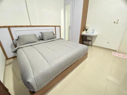 1 cama grande en una habitación blanca con en MJ Guest House Pusat Kota Malili Mitra RedDoorz, en Malili