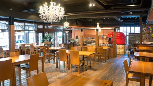 a restaurant with wooden tables and chairs and a chandelier at APA Hotel Kochi in Kochi