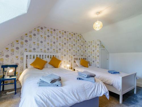 twee bedden in een kamer met gele en blauwe handdoeken bij 19 South Street in Grantown on Spey