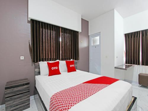 a bedroom with a large bed with red pillows at Super OYO Capital O 91665 D'prof Exclusive Guesthouse in Semarang