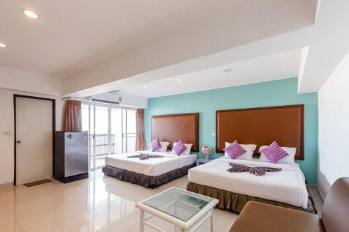 a hotel room with two beds and a table at Latin Garden Hotel in Bangkok