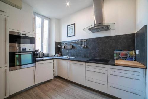 a kitchen with white cabinets and black counter tops at Superbe 120m2 au Suquet - Property With Style in Cannes