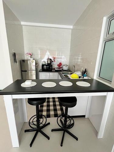 a kitchen with a counter with three bar stools at Aina Staycation, Metrocity in Kuching