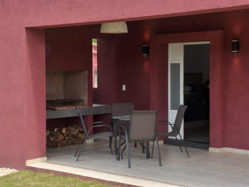 eine Terrasse mit einem Tisch und Stühlen neben einer roten Wand in der Unterkunft Casonas de Nono in Nono