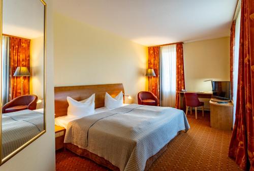 ein Hotelzimmer mit einem Bett und einem Spiegel in der Unterkunft Hotel Mercator Itzehoe-Klosterforst in Itzehoe