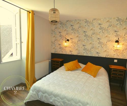 a bedroom with a white bed with two orange pillows at L'authentique Martelaise PISCINE CHAUFFEE in Martel