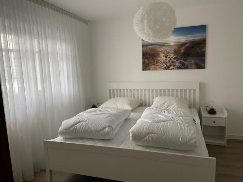 a white bedroom with two pillows on a bed at SaßStähler, FW6 in Zingst