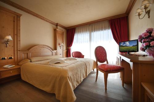 a bedroom with a bed and a desk and a television at Hotel Valtellina in Livigno
