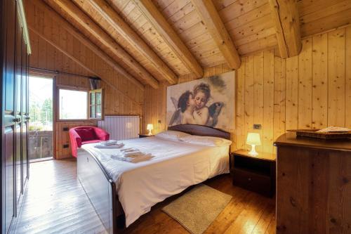 1 dormitorio con 1 cama y una pintura en la pared en Incanto Walser Apartments Testa, en Macugnaga