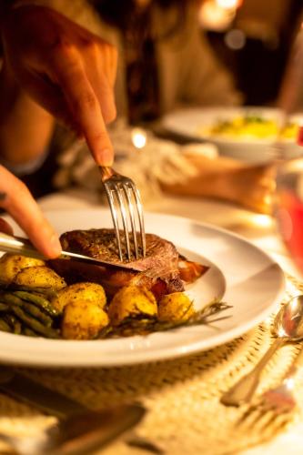 a person cutting a piece of meat on a plate with a fork at CASA ABRACADABRA in Marrakech