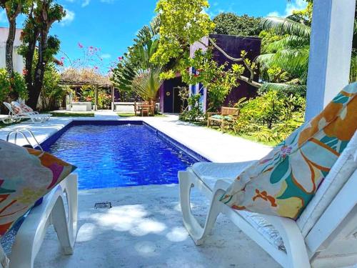 a swimming pool with two lawn chairs next to it at Villa Ostello Pousada in Paripueira