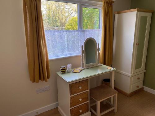 a dressing table with a mirror and a window at Beekeepers Cabin in Reepham