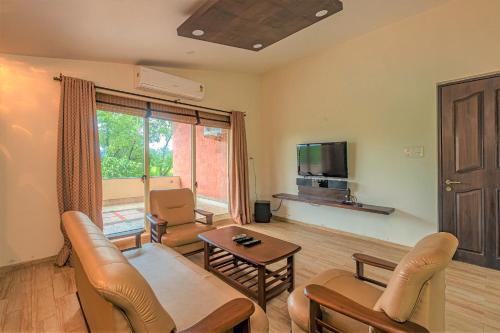 a living room with a couch and a tv at SaffronStays Ananya, Karjat in Karjat