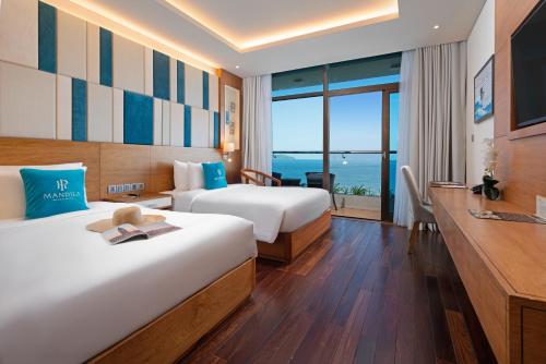 a hotel room with two beds and a view of the ocean at Mandila Beach Hotel Danang in Danang
