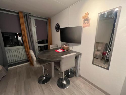 a room with a table and chairs and a television at Coquet et accueillant Studio montagne la Mongie in Bagnères-de-Bigorre