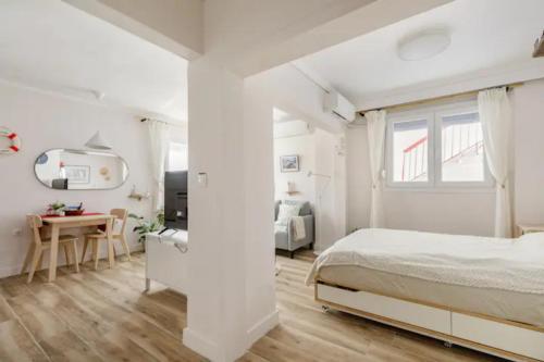 a white bedroom with a bed and a desk at Lovely small (parterre) apartment in Thessaloniki in Thessaloniki