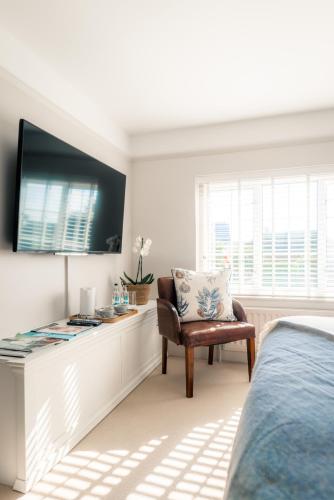a bedroom with a bed and a chair and a tv at The Seaview, East Preston in Littlehampton