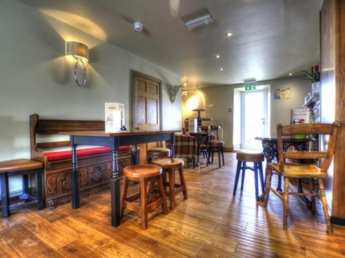 a bar with wooden stools and a table and chairs at Masons Freehouse in Ingleton