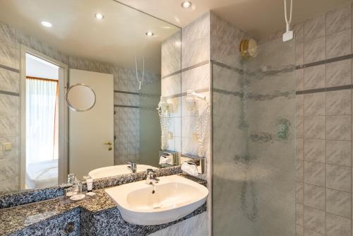 ein Bad mit einem Waschbecken und einer Dusche in der Unterkunft Hotel Mercator Itzehoe-Klosterforst in Itzehoe